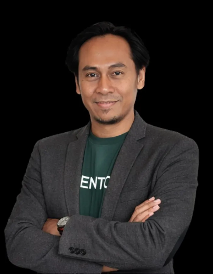 Eko Novianto berdiri bersedekap mengenakan blazer abu dan kaos hijau